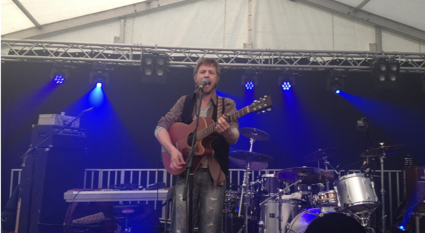 Ciaran singing and playing acoustic guitar on a festival stage