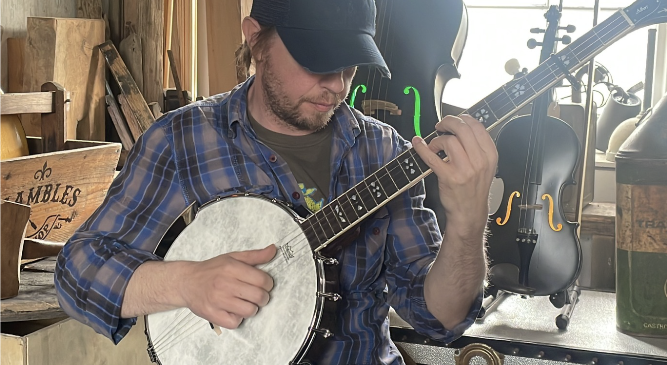 Ciaran playing banjo surrounded by instruments